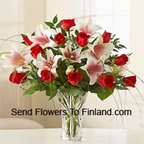 Rote Rosen und rosa Lilien mit saisonalen Füllmaterialien in einer Glasvase